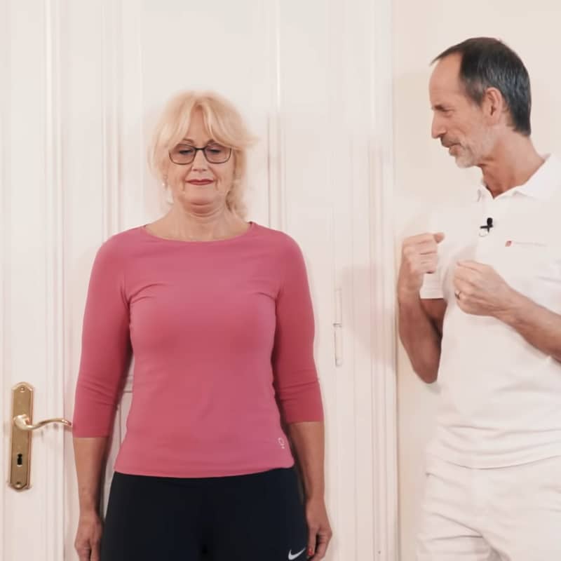 A woman is standing with her back against the wall while Roland Liebscher-Bracht looks on.