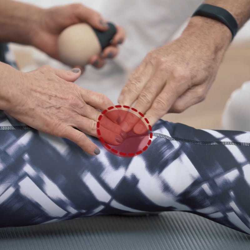 Two hands are pressing against the side of a knee.