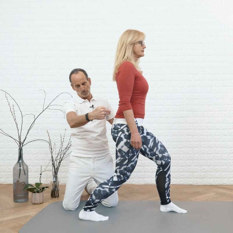 A woman is standing with her legs bent while Roland Liebscher-Bracht looks on.
