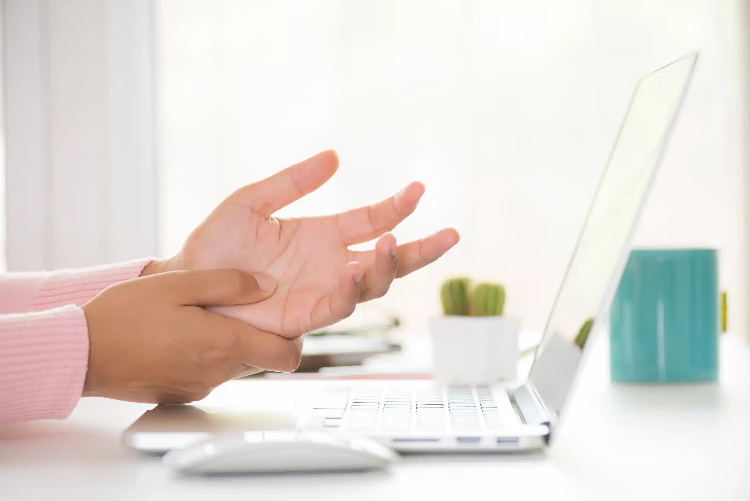 A hand rubbing the opposite wrist at a keyboard.
