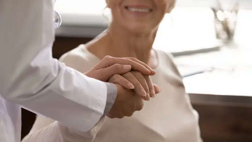 Closeup of a woman holding a doctors hand.