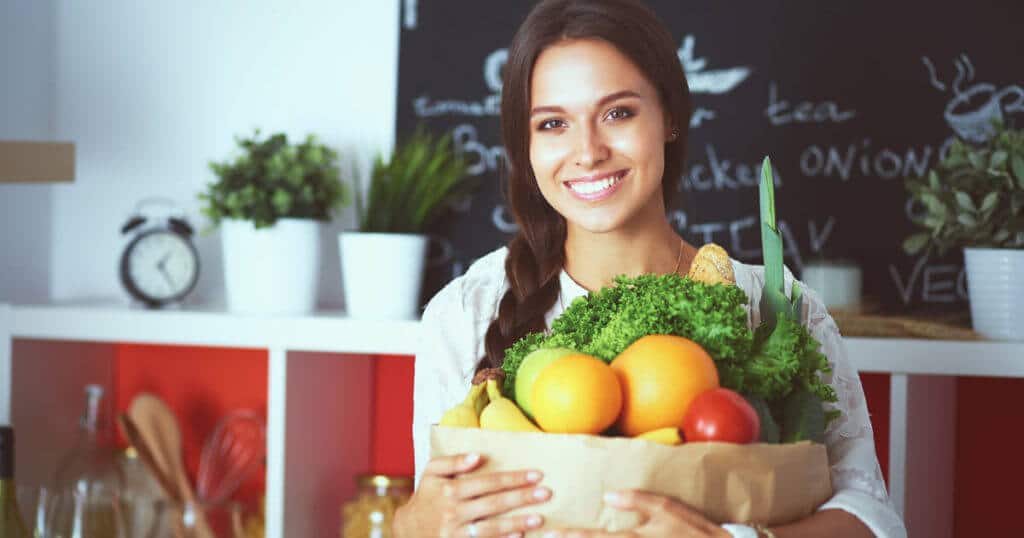 Eine Veganerin mit einem Korb voll Obst und Gemüse