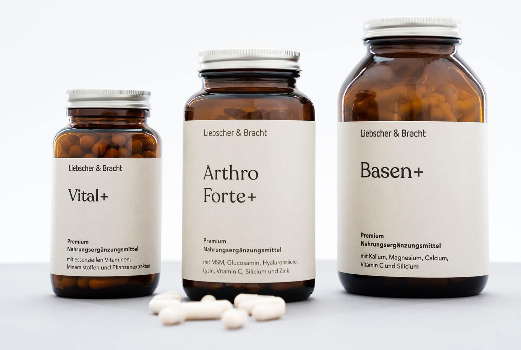 Abgebildet sind drei Nahrungsergänzungsmittel in Braunglasflaschen. Die linke Flasche steht auf der umweltfreundlichen Verpackung, die mittlere steht neben ihrer umweltfreundlichen Verpackung, die rechte steht auf ihrer umweltfreundlichen Verpackung