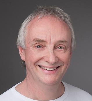 Der Schmerztherapeut aus Roggwil, André Henzmann hat hellgraue Haare und trägt ein weißes T-Shirt. Das Portraitfoto ist vor einem grauen Hintergrund aufgenommen worden.