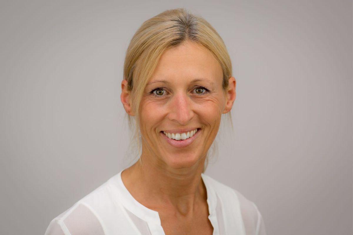 Das Portraitfoto zeigt Karin Hanrieder aus Zolling. Der Hintergrund ist hellgrau. Sie trägt ihren blonden Haare zu einem Zopf, wobei der schräge Pony herausschaut und eine weiße Bluse. Sie lächelt in die Kamera.