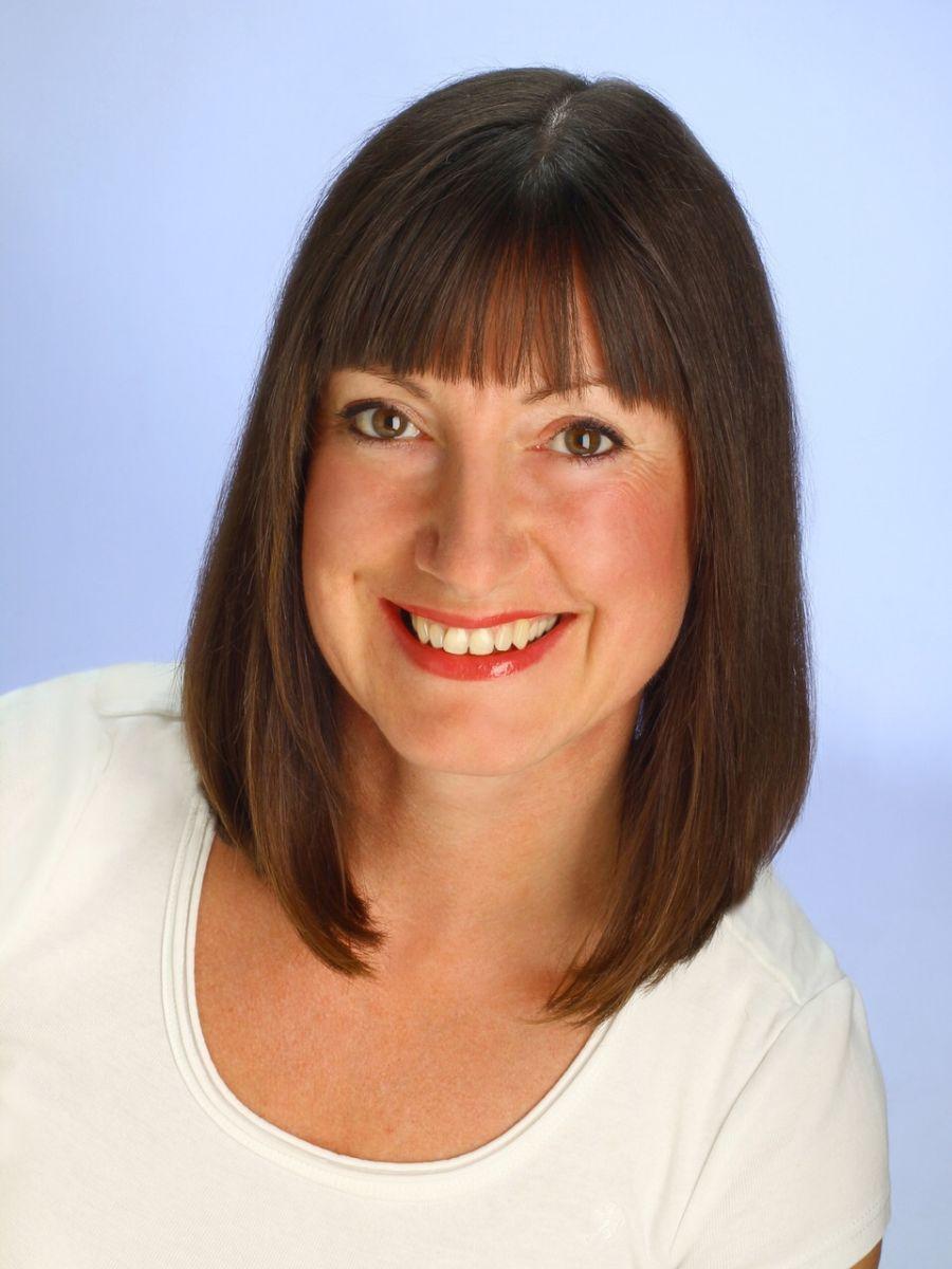 Vor dem hellblauen Hintergrund sieht man als Portrait die Schmerztherapeutin Ramona Franke sympathisch lächeln. Sie hat braune mittellange Haare mit Pony. Sie trägt ein weißes T-Shirt.