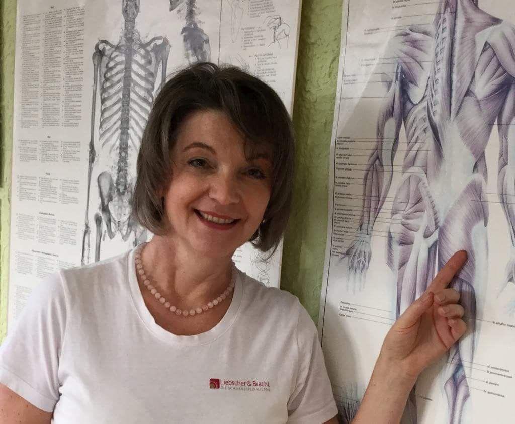 Auf dem Foto ist Simone Baalhorn aus 19057 Schwerin zu sehen wie sie auf ein medizinisches Plakat neben sich zeigt. Sie hat kinnlanges braunes Haar und trägt neben einer Perlenkette ein weißes T-Shirt.