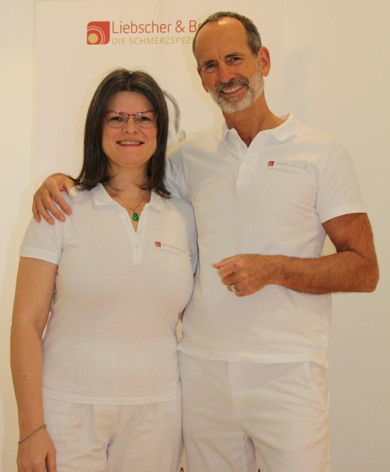 Susanne Höllbacher aus Bayreuth steht grinsend vor einem weißen Hintergrund. Sie trägt einen hellbeigen Pullover und eine randlose Brille. Ihre Haare sind dunkelbraun und schulterlang.