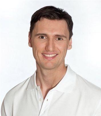 Das Portraitbild zeigt den Physiotherapeuten Markus Teichmann. Er hat braune Haare und trägt ein weißes Polo T-Shirt.