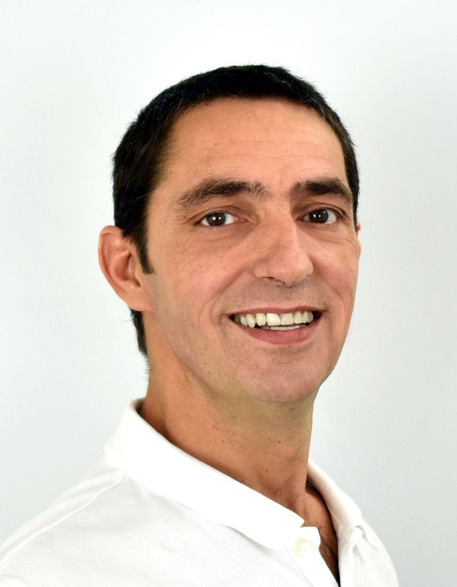 Das Portraitfoto zeigt Guido Bucher aus der EIM Praxis in Lachen schräg von der Seite. Er hat schwarze kurze Haare und trägt ein weißes Polo T-Shirt.