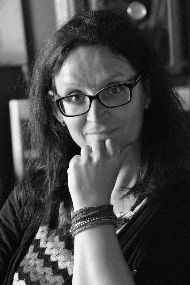 Das schwarz-weiß Foto zeigt Carina Schäfer-Sowinski aus 56564 Neuwied. Sie hat eine Hand an ihr Kinn gelegt und schaut freundlich in die Kamera. Sie hat lange dunkle Haare und eine eckige Brille.