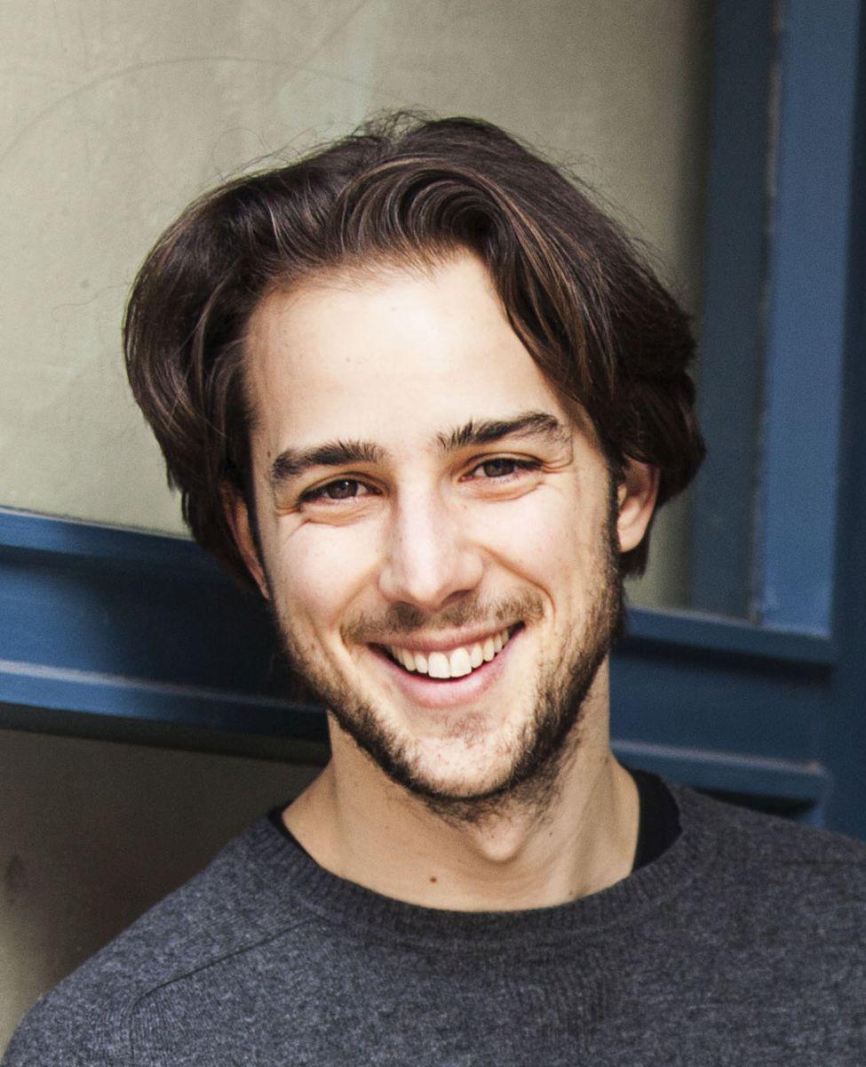Maximilian Schön, Qualitätspartner Liebscher & Bracht, steht vor einer blau-grauen Tür. Das Portraitfoto zeigt ihn mit längeren braunen Haaren, Bart und einem dunkelgrauen Pullover.