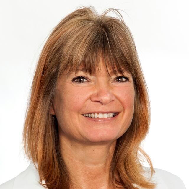 Das Foto zeigt die Physiotherapeutin Claudie Halfter aus Haan. Sie hat braune mittellange Haare und Pony. Sie trägt ein weißes Polo T-Shirt mit Liebscher & Bracht Aufdruck.