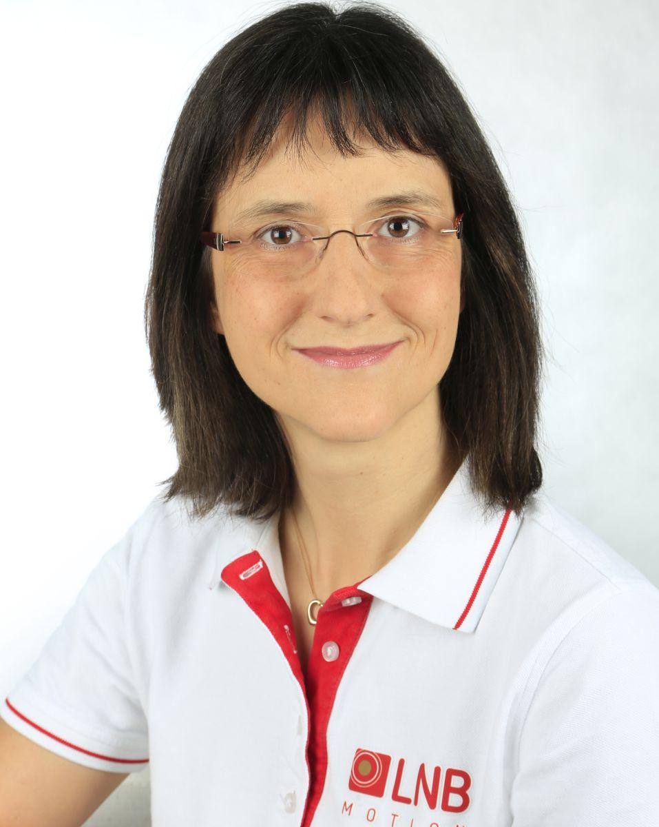 Das Foto zeigt Susanne Carl-Schröder vor einem weißen Hintergrund. Sie hat schulterlange braune Haare und einen geraden Pony. Sie trägt eine randlose Brille und ein weißes Liebscher & Bracht Polo T-Shirt.