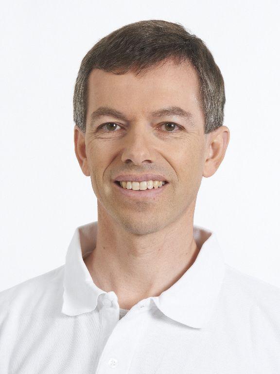 Das Portraitfoto von Markus Müller ist vor weißem Hintergrund aufgenommen. Er hat braunes Haar und trägt ein weißes Polo T-Shirt.