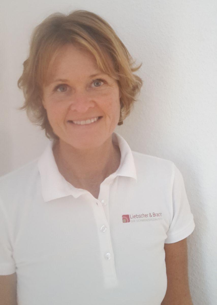 Das Foto zeigt Babett Titzmann in einem weißen Liebscher & Bracht Polo T-Shirt. Sie steht an einer weißen Wand gelehnt und hat blonde mittellange Haare.