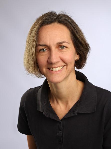 Das Portraitfoto zeigt die Physiotherapeutin Simone Aigle aus Blaustein. Sie steht vor einem hellgrauen Hintergrund. Ihre braunen Haare sind Kinn lang und dazu trägt sie ein schwarzes Polo T-Shirt.