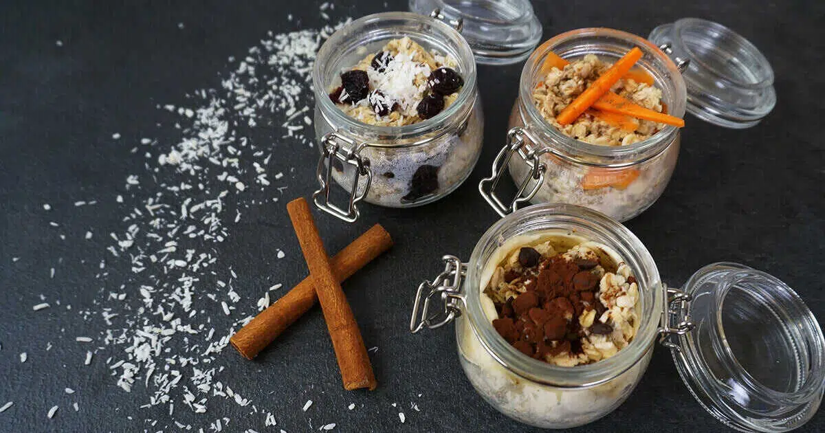 Drei Porridge-Varianten in Gläsern sind auf einer Schieferplatte angerichtet.