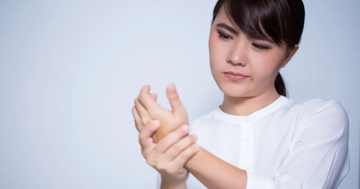 Eine Frau hat Daumenschmerzen durch Büroarbeit