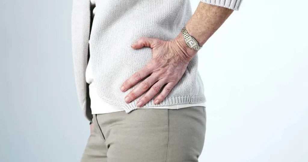 Eine alte Frau hält sich ihre von Hüftarthrose schmerzende Hüfte