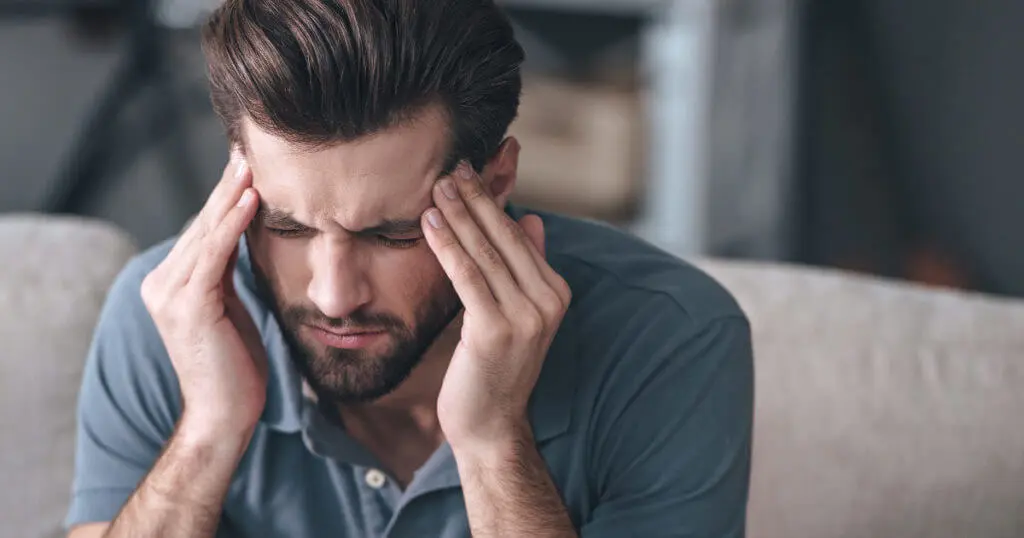 Mann hält sich den Kopf bei starken Kopfschmerzen und Gesichtsschmerzen
