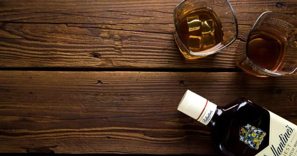 Das alkoholische Getränk Scotch steht auf einem Holztisch - Alkohol ist besonders bei Arthrose ungesund.