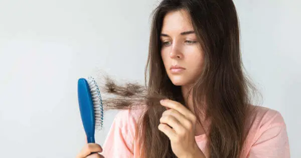 Frau rupft lose Haare aus der Bürste