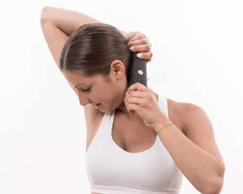 Eine Frau in weißem Sporttop bearbeitet ihre seitliche Nackenmuskulatur mit einer Medi-Faszienrolle von Liebscher & Bracht.
