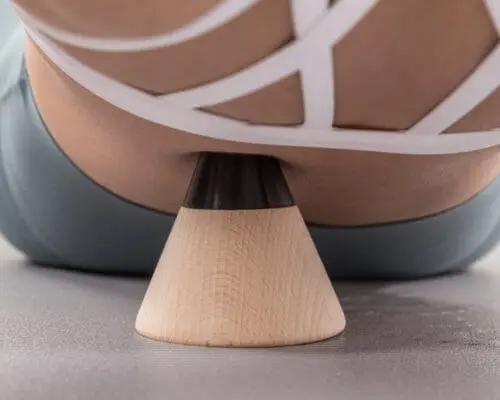 Anwendung des Schmerzfrei-Drückers auf dem Boden. Eine Patientin drückt einen Knochenpunkt am Rücken.