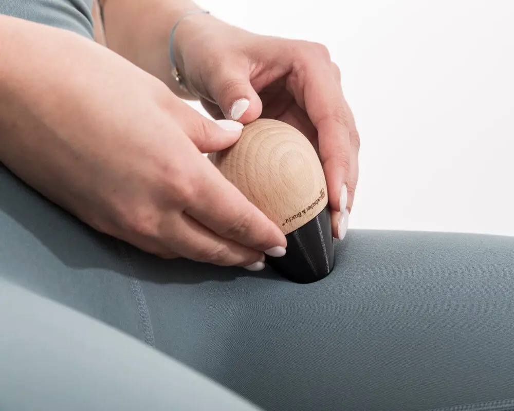 Anwendung des Schmerzfrei-Drückers mit kugelförmigem Griffstück. Die Patientin drückt einen Knochenpunkt am Oberschenkel.