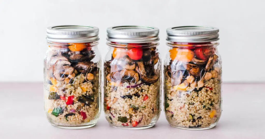 Drei Einmachgläser gefüllt mit Quinoa und Gemüse