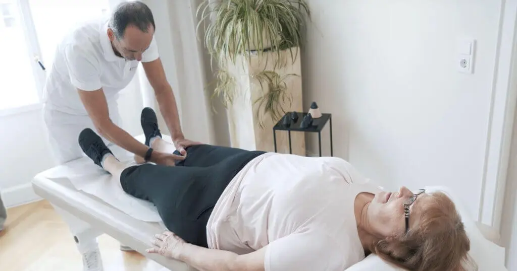 Roland Liebscher-Bracht wendet drückt bei einer Patienten einen Osteopressur-Punkt am Knie