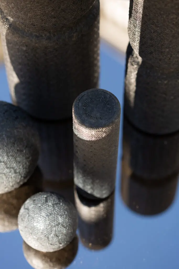 Foto verschiedener Faszienrollen und Faszienkugeln von Liebscher & Bracht, die auf einem Tisch stehen und sich in der gläsernen Tischplatte spiegeln