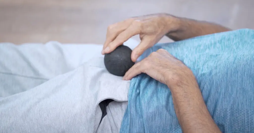 Mann rollt mit einem Faszienball über den vorderen Körperbereich, um Rückenschmerzen im unteren Rücken zu lindern