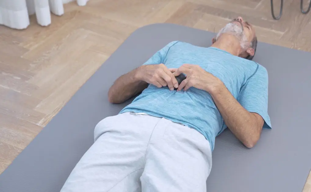 Mann rollt mit einem Faszienball über den vorderen Körperbereich, um Rückenschmerzen im unteren Rücken zu lindern