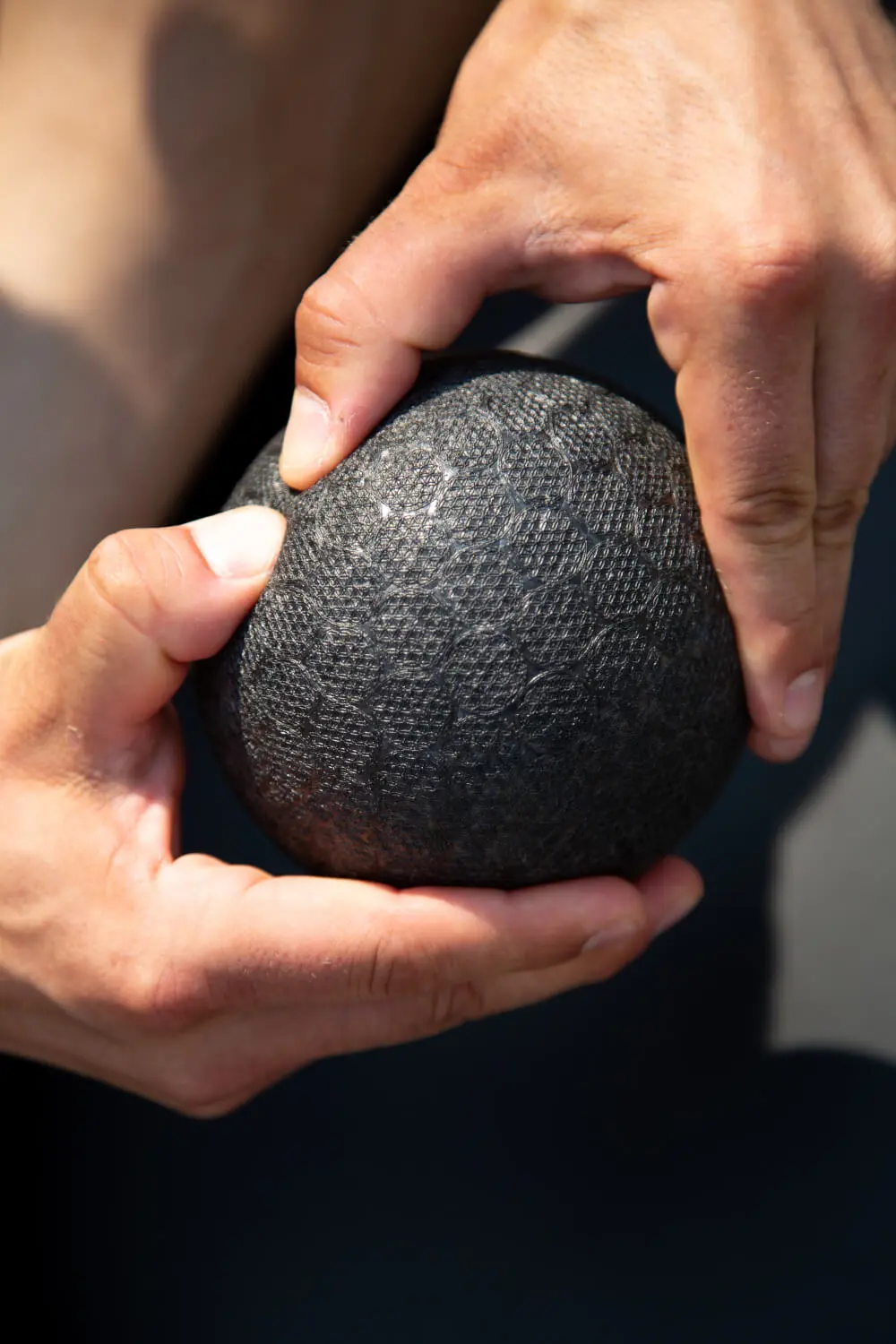 Zu sehen ist eine Hand, die eine Faszienkugel hält und in die weiche Oberfläche des Balles hineindrückt