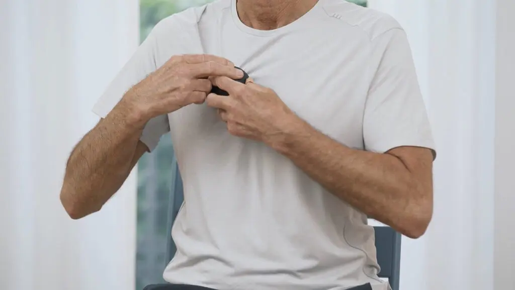 Ein Mann hält eine Faszienkugel mit beiden Händen und rollt damit entang des Brustbeins