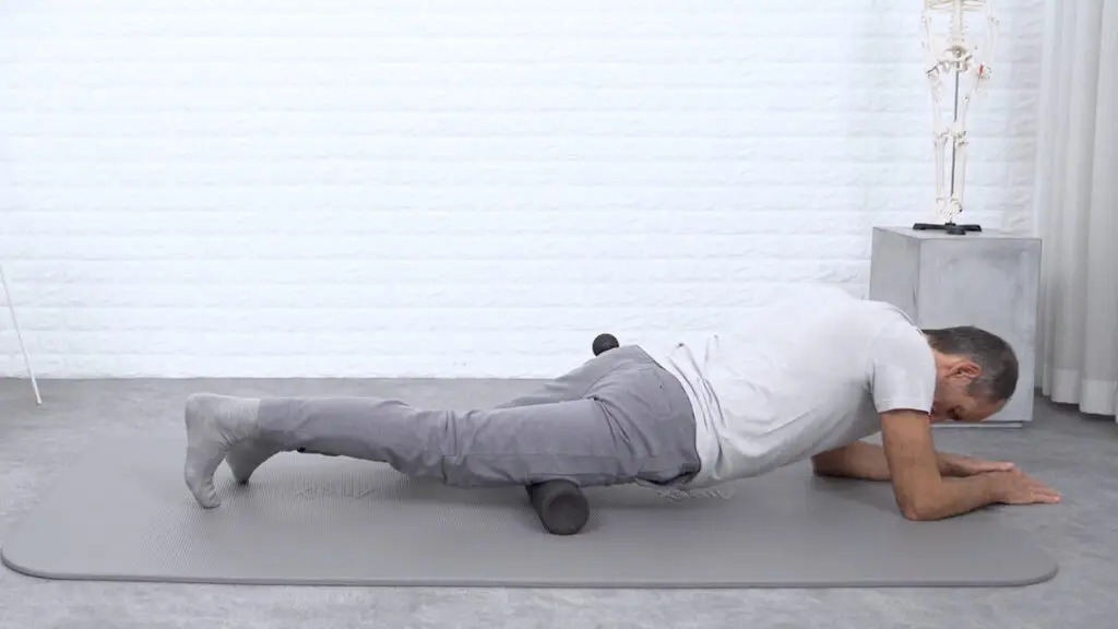 Ein Mann liegt mit dem Oberschenkel auf einer Faszienrolle und führt so eine Faszien-Rollmassage am Oberschenkel durch