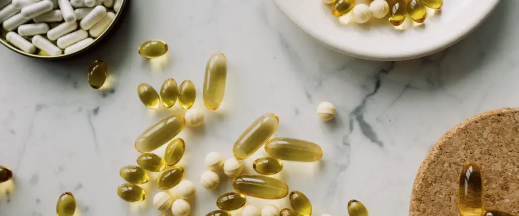 Pillen in gelb, und weiss liegen auf einem Marmortisch und Tellern verteilt.