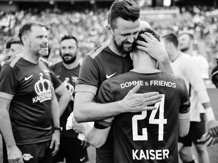 Ein Mann umarmt einen Fußballspieler auf dem Spielfeld.