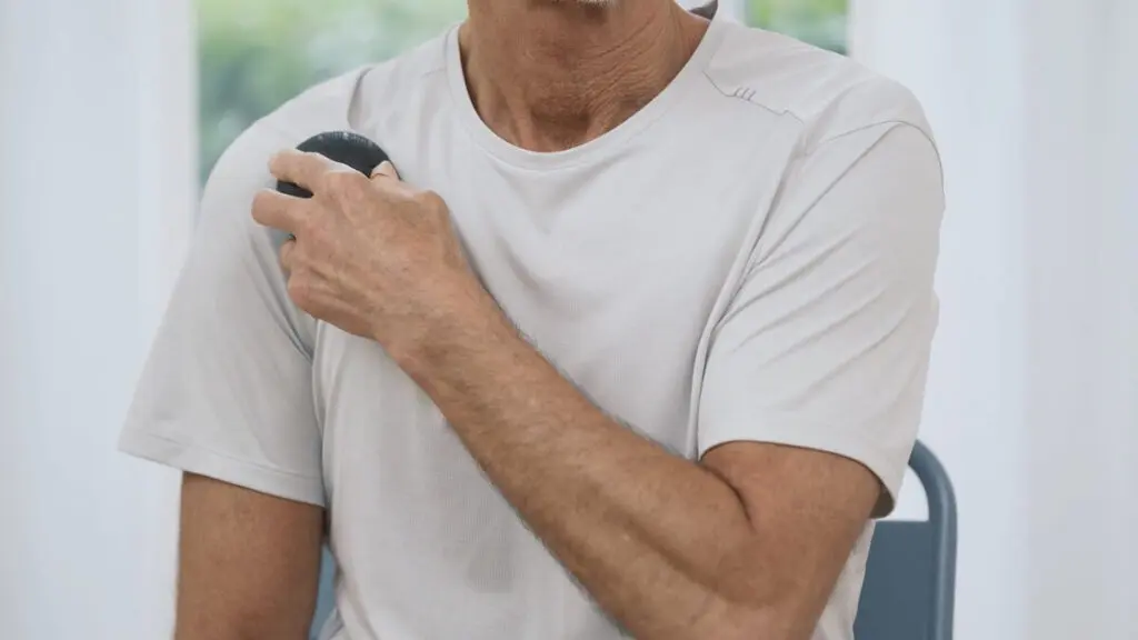 Ein Mann hält eine Faszienkugel mit beiden Händen und rollt damit entang des Brustbeins