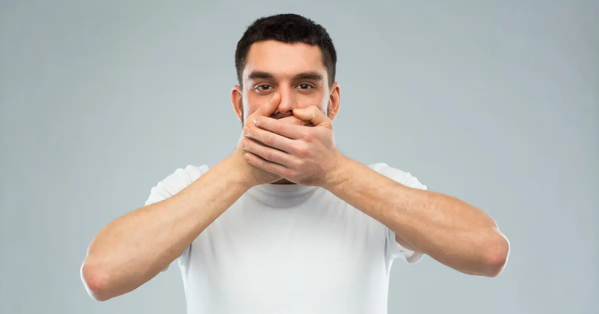 Ein Mann fasst sich mit beiden Händen vor den Mund.
