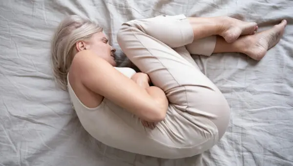 Eine Frau liegt gekrümmt auf dem Bett