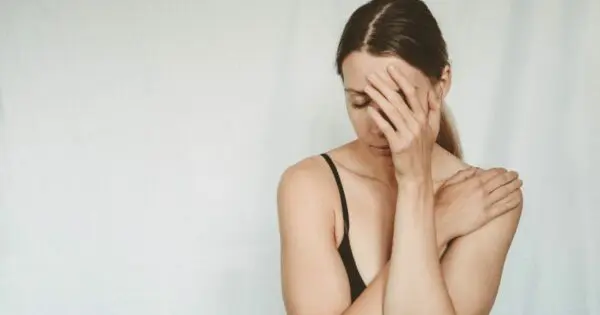 Eine Frau in schwarzem Top hält sich erschöpft eine Hand vors Gesicht.