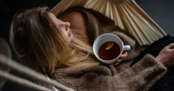 Eine Frau sitzt in einer Hängematte und trinkt Tee