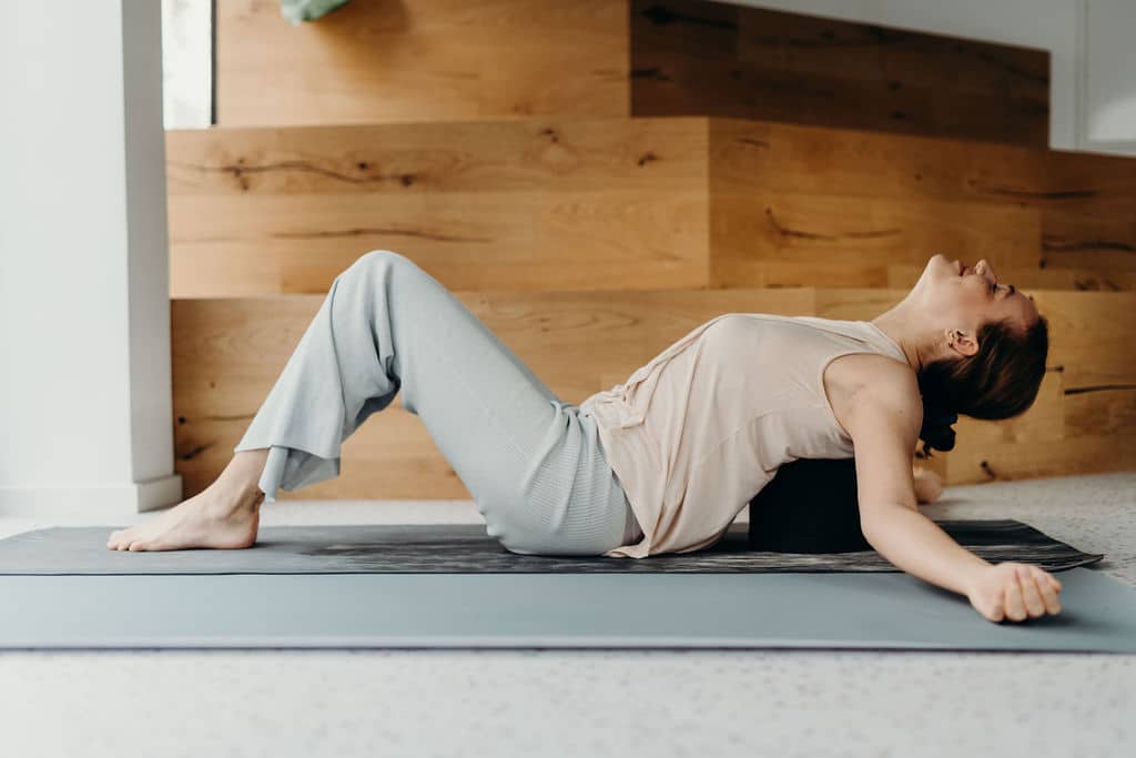 Eine Frau dehnt ihren Rücken auf dem Rückenretter von Liebscher & Bracht.