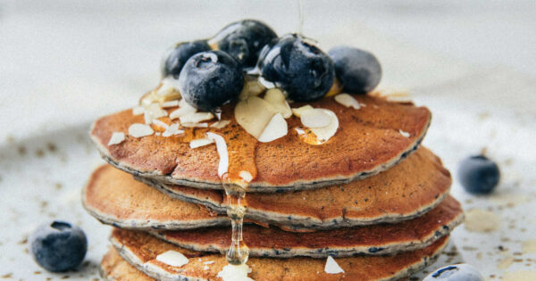 Ein Pfannkuchenstapel mit Blaubeeren ist auf einem Teller angerichtet