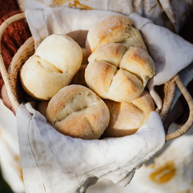 Viele helle Brötchen liegen in einem Brotkorb.