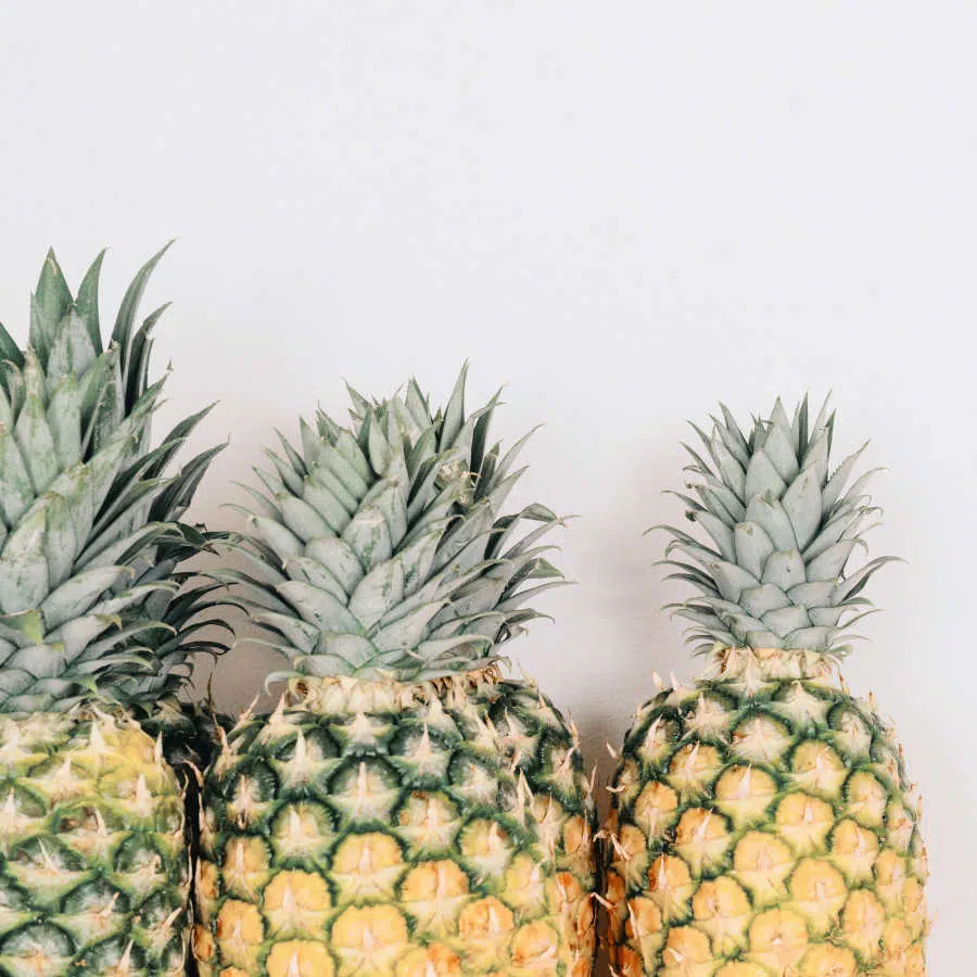 Drei Ananas stehen nebeneinander vor einem weißen Hintergrund