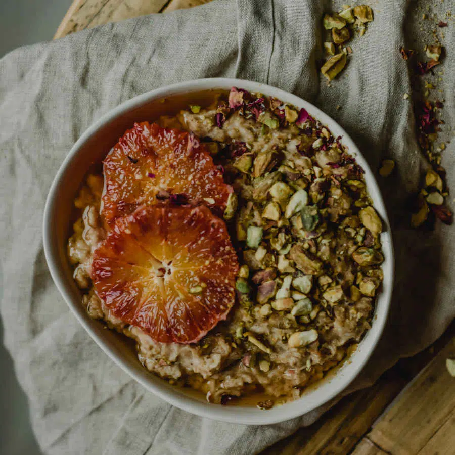 Eine Schale mit basischem Frühstücksbrei ist abgebildet. Der Brei ist getoppt mit zwei Scheiben Grapefruit und Pistazien